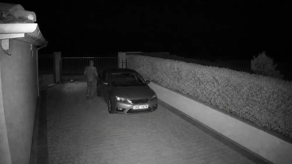 Σκηνή επίδειξης, νυχτερινή λήψη με υπέρυθρο: αυτοκίνητο μπροστά σε αυλόπορτα και κάποιος που περπατά δίπλα του